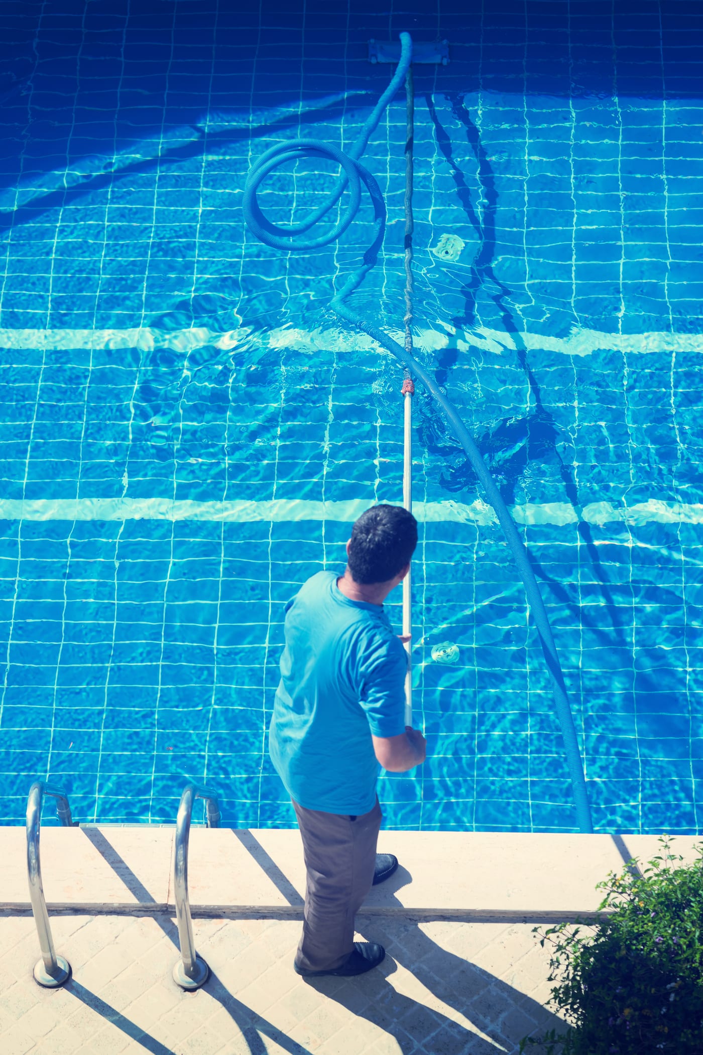 Georgia Plaster & Tile technician hand-cleaning a pool waterline